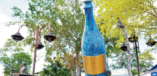 Atractivo. Esta enorme botella de mabí champagne seibano adorna la Plaza Tomás Otto Duvergé, inaugurada en 2008 en la avenida Manuela Díez. A un costado del parque, en la calle Duvergé, está la casona donde se vende la refrescante bebida. Iris Lizardo/LD