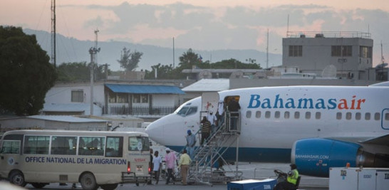 Parte de 290 haitianos repatriados de las Bahamas bajan de un avión de ese país en el aeropuerto internacional Toussaint Louverture, en Puerto Príncipe, el 26 de noviembre de 2014.