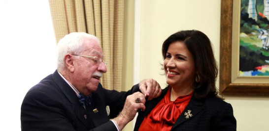 Roberto Weill, presidente del Pabellón de la Fama del Béisbol Latino, le coloca un pin de esa entidad a la doctora Margarita Cedeño de Fernández.