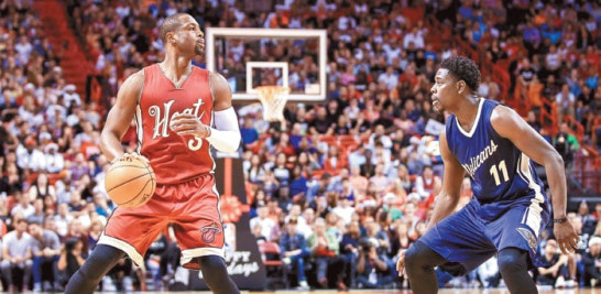 Dwyane Wade, de los Heat de Miami, maneja el balón frente a Jrue Holiday, de New Orleans, durante el partido de ayer en el baloncesto de la NBA.