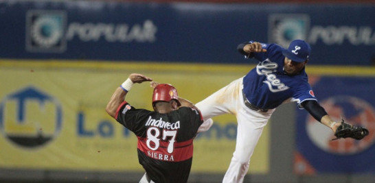 El segunda base Anderson Hernández, del Licey, trata de poner out al jardinero Moisés Sierra, del Escogido, quien se estafó la intermedia en el séptimo episodio.