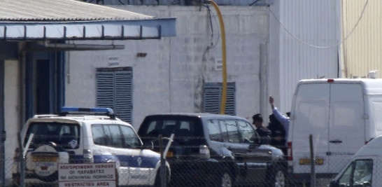 Una persona, que se cree podría ser el secuestrador del avión de EgyptAir (tras la furgoneta de la derecha), levanta los brazos en alto mientras es arrestado por la policía en el aeropuerto de Larnaca (Chipre) hoy, 29 de marzo de 2016.