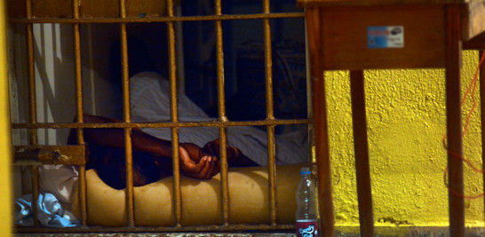 Pabellón. Una persona duerme en el suelo, en una celda de "Alaska". A la izquierda, un policía lee la Biblia por la mañana.