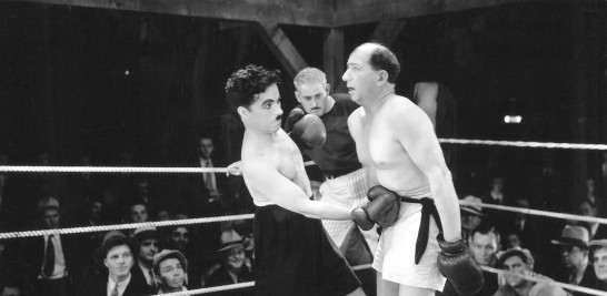 Chaplin se enrola en una pelea de boxeo para conseguir dinero.