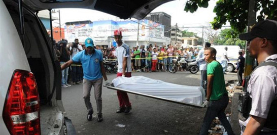 Víctima. En esta imagen, dos hombres cargan una camilla con el cadáver de un chofer asesinado en Pedro Brand.