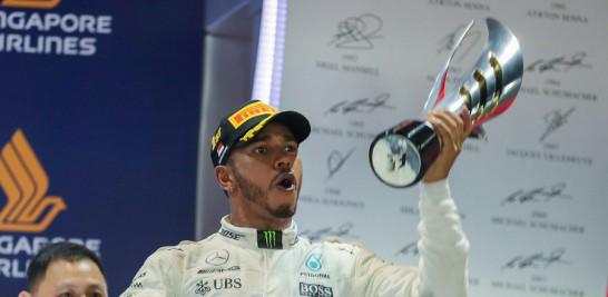 El piloto británico Lewis Hamilton, de Mercedes AMG GP, celebra levantando en alto el trofeo después de ganar el Gran Premio de Fórmula Uno de Singapur.