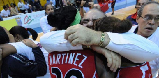 Cristóbal Marte, se abraza efusivamente con dos jugadoras luego de un triunfo de la selección nacional.
