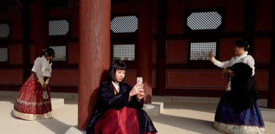 3) varias adolescentes surcoreanas con el traje tradicional Hanbok toman fotos en el Palacio Gyeongbokgung de Seúl;