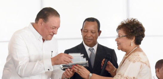 Alejandro Montás recibe una placa de Juan Coronado y Elsa Ogando.