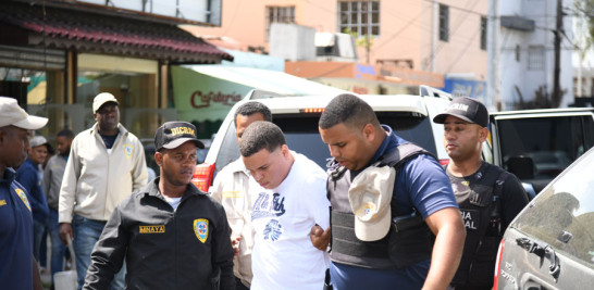 Franklin Junior Merán (Rubirosa), con franela blanca, implicado en el ataque a David Ortiz, es conducido al destacamento Felicidad, de Los Mina, por tres oficiales de la Dicrim.