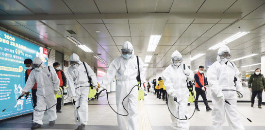 Trabajadores con equipo de protección desinfectan una estación de Metro como precaución contra el coronavirus, en Corea del Sur. /AP