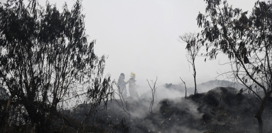 Dos bomberos tratan de apagar parte de las llamas en el vertedero de Duquesa, en Santo Domingo Norte. JORGE CRUZ/LISTINDIARIO