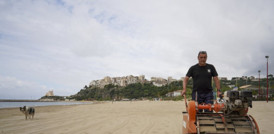 Un empleado de un hotel nivela la playa de Sperlonga, Italia, el 28 de abril del 2020. A esta altura del año ya debería haber gente en la playa, pero los balnearios siguen cerrados por la cuarentena del coronavirus, a la espera de noticias acerca de cuándo pueden abrir. (AP Photo/Andrew Medichini)