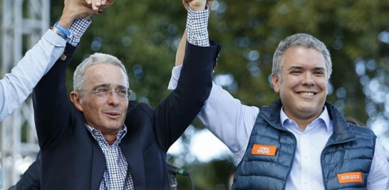 Iván Duque, entonces candidato a la presidencia de Colombia, levanta la mano a su mentor, Álvaro Uribe, durante la campaña, el 20 de mayo de 2018. AP