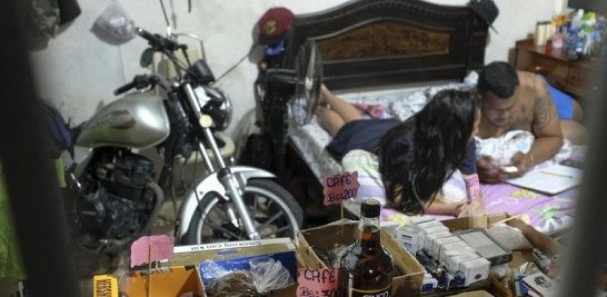 Alimentos, cigarrillos y velas se encuentran a la venta detrás de las rejas antirrobo de una residencia privada, donde una pareja calcula sus ventas desde su cama. Foto: AP/Matias Delacroix.