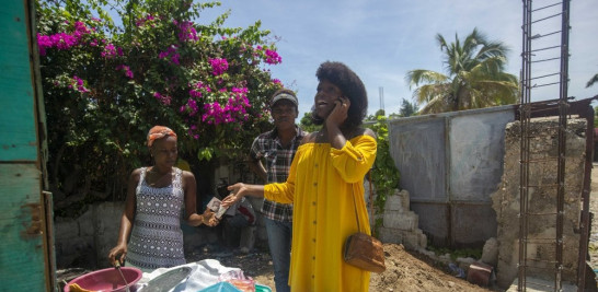 Semi Kaefra Alisha Fermond,m una mujer transexual, paga a una vendedora ambulante por una pizza creole, en Puerto Príncipe, Haití, el 15 de agosto de 2020. Estoy orgullosa de mí misma porque ahora puedo vestir ropa de mujer e ir a todas partes", afirmó. En la casa de mi madre no puedo ser así. (AP Foto/Dieu Nalio Chery)