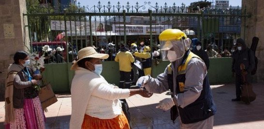 Un trabajador toma la temperatura de una mujer para evitar la propagación del nuevo coronavirus en la entrada del Cementerio General de La Paz, Bolivia. Foto: AP/Juan Karita.
