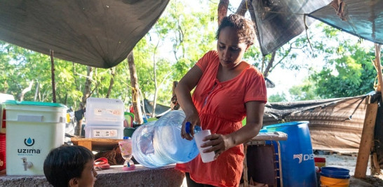 Jacqueline Salgado recibe una taza de agua para su hijo en un campamento para migrantes en Matamoros, México, al otro lado de la frontera de Brownsville, Texas, el 6 de agosto de 2020. (Ilana Panich-Linsman/The New York Times).