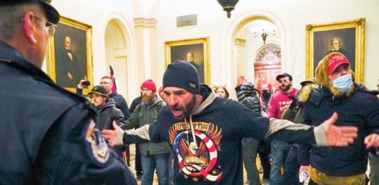 Uno de los simpatizantes de Trump enfrenta a un policía en la sede del Congreso. AP