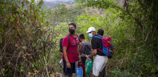 Migrantes hondureños observan un control policial mientras toman una ruta alternativa para evitar ser detenidos, en Chiquimula, Guatemala, el 19 de enero de 2021. Mientras Guatemala se centraba en la primera caravana del año que partía hacia el norte, otros migrantes pusieron el mismo rumbo en grupos más pequeños y discretos. Fue durante la caravana del mes pasado cuando los refugios del sur de México comenzaron a registrar un incremento en el número de inquilinos, sobre todo migrantes hondureños. (AP Foto/Oliver de Ros)