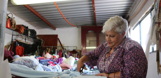 La costurera Irma de la Parra corta una camiseta usada por una persona que murió de COVID-19 en su taller en Ciudad de México el sábado 24 de abril de 2021. (AP Foto/Ginnette Riquelme)