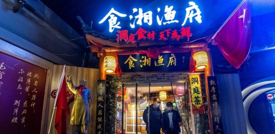 6.-Dos hombres salen de un restaurante junto a una estatua de Mao Zhedong, revolucionario comunista chino y fundador de la República Popular China, en Shanghái (China). EFE/EPA/ALEX PLAVEVSKI