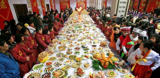 6.-Varias personas se reúnen alrededor de una gran mesa durante una muestra de platos diseñados para el muy próximo en una localidad de China. EFE/str