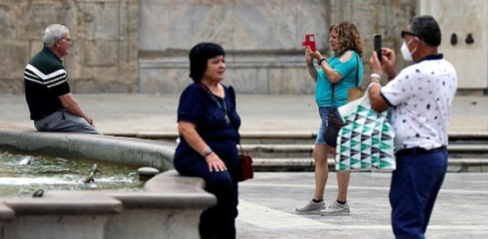 5.-Varios turistas se toman sendas fotografías ante la fuente situada en la plaza de la Virgen de Valencia, en pleno centro histórico de la ciudad de Valencia (España). EFE/Manuel Bruque