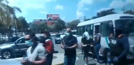 Unos18 arrestados en el operativo del MP bajan de un autobús y se dirigen al Palacio de Justicia de Santiago.