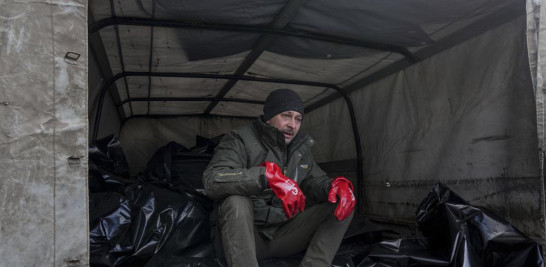 Un trabajador de la morgue se sienta sobre bolsas para cadáveres antes de ser transportados para ser enterrados en una fosa común en las afueras de Mariupol, Ucrania, el miércoles 9 de marzo de 2022. Foto: Evgeniy Maloletka/AP.