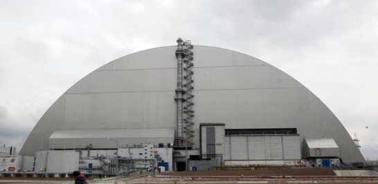 ARCHIVO - Un hombre pasa frente a un refugio que cubre el reactor que explotó en la planta nuclear de Chernobyl, en Chernobyl, Ucrania, el jueves 15 de abril de 2021. Cuando los combates por la invasión de Rusia a Ucrania provocaron cortes de energía en el crítico sistema de enfriamiento de la cerrada Chernobyl. central nuclear, algunos temían que el combustible nuclear gastado se sobrecalentara. Pero los expertos nucleares dicen que no hay peligro inminente porque el tiempo y la física están del lado de la seguridad. (Foto AP/Efrem Lukatsky, archivo)