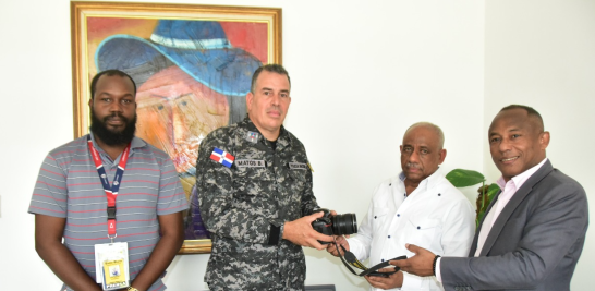 El coronel Iván Matos, de la Digesett, entrega la cámara fotográfica a Tomás Aquino Méndez. Presentes, el fotorreportero Raúl Asencio y Roberto Valenzuela, de Digesett.