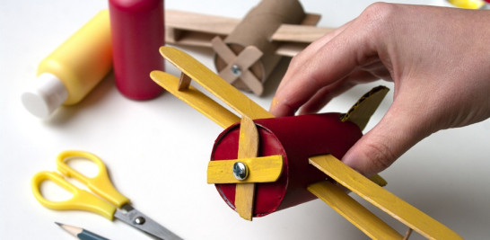 Si ya consideras que puedes hacer objetos más elaborados, atrévete con este avión antiguo cerrando el rollo de cartón y agregando palitos de paletas y cartón así como se ve en la imagen.