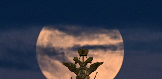 La luna llena, también conocida como luna de sangre de flores, se representa detrás del águila bicéfala, el símbolo nacional de Rusia, en lo alto de un edificio en la Plaza Roja en el centro de Moscú. Kirill KUDRYAVTSEV / AFP