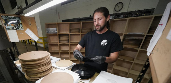 Ricky Riehl inspecciona discos de vinilo terminados en busca de defectos antes de que sean empaquetados, en las instalaciones de United Record Pressing, el jueves 23 de junio de 2022 en Nashville, Tennessee. (Foto AP/Mark Humphrey).