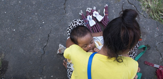 Una mujer amamanta a un niño mientras vende velas en el patio de una iglesia en Filipinas. Del 1 al 7 de agosto se celebra la Semana Mundial de la Lactancia Materna. ISTOCK