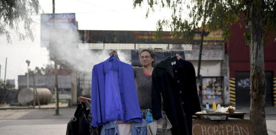 Una vendedora sostiene prendas de segunda mano en un mercado donde la gente puede comprar o intercambiar productos en las afueras de Buenos Aires, Argentina, el miércoles 10 de agosto de 2022. AP Foto/Natacha Pisarenko