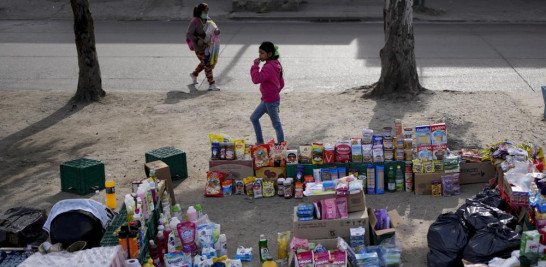 Los peatones pasan frente a un mercado al aire libre donde la gente puede comprar o intercambiar productos en las afueras de Buenos Aires, Argentina, el miércoles 10 de agosto de 2022. AP Foto/Natacha Pisarenko