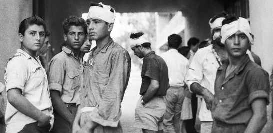 Jóvenes grecochipriotas, algunos con la cabeza vendada, se paran frente a un hospital en Famagusta, Chipre, el 4 de octubre de 1958. Dijeron que sus heridas se recibieron en las operaciones intensivas de redadas realizadas por las fuerzas de seguridad el día después de que los terroristas de la EOKA mataran a tiros a un británico. mujer e hirió a otra cuando salían de un comercio en la calle Hermes de Famagusta. (Foto AP, Archivo)