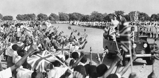 Miles de jóvenes ondean banderas y aplauden mientras la reina Isabel II y el príncipe Felipe, recorren el hipódromo de Kaduna en el norte de Nigeria el 2 de febrero de 1956.