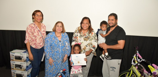 Santa de la Cruz, Mirma Pimentel y Siddy Roque entregan el premio a Ensley Cabral, junto a su hermano Evan, y su padre Wilmer Cabral.