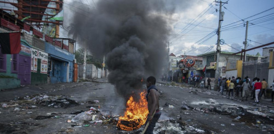 Un hombre pasa junto a llantas en llamas colocadas por manifestantes durante una protesta que exigía la renuncia del primer ministro Ariel Henry en el área de Delmas en Puerto Príncipe, Haití, el lunes 10 de octubre de 2022. (Foto AP/Odelyn Joseph)