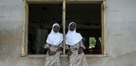 Los gemelos Taiwo Asisi, a la izquierda, y Kehinde Asisi, de 13 años, estudiantes de la escuela secundaria de gramática Igbo-Ora asisten al festival anual de gemelos en Igbo-Ora, suroeste de Nigeria, el sábado 8 de octubre de 2022. (Foto AP/Sunday Alamba)