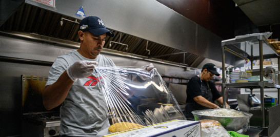 El venezolano Gustavo Méndez prepara comida en el restaurante donde trabaja, en el barrio Queens de la ciudad de Nueva York.  / afp