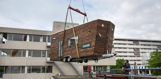 Subiendo una vivienda estilo mobile home compacta a la azotea durante un ensayo. Foto: Dakdorpen.