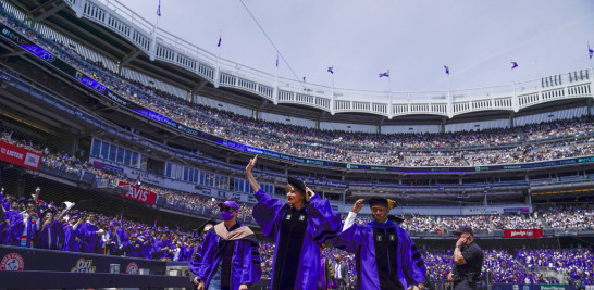 Taylor Swift, centro, saluda a graduados al participar en una graduación en de la Universidad de Nueva York en el Yankee Stadium en Nueva York, el miércoles 18 de mayo de 2022. (Foto AP/Seth Wenig)