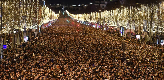 Gente se reúne en los Campos Elíseos mientras esperan los fuegos artificiales de Nochevieja en París el 31 de diciembre de 2022. Foto: Julien De Rosa/AFP.