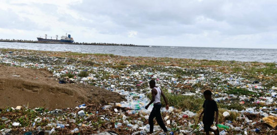 Jóvenes caminando sobre la basura que rodea la Playa Montesinos