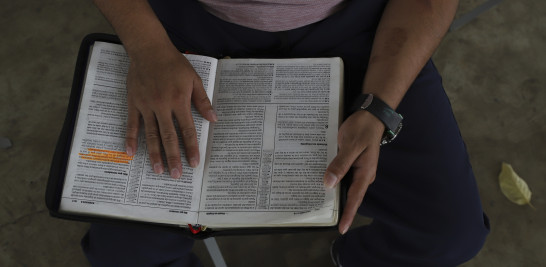 Un hombre joven que estuvo en prisión por formar parte de una pandilla lee la Biblia durante las horas de visitas familiares en el centro de rehabilitación "Vida Libre", en Santa Ana, El Salvador, el sábado 29 de abril de 2023.