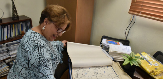 La ingeniera Gloria Ceballos ojea los viejos registros que confeccionaron en 1979 para tratar de seguir el curso del huracán David.